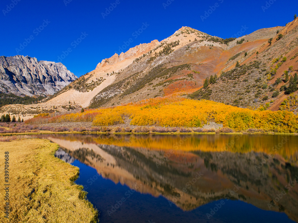 Aerial view of North Lake with reflections of fall aspen and mountains .