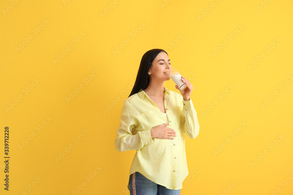 Beautiful pregnant woman drinking milk on color background Beautiful pregnant woman drinking milk on color background