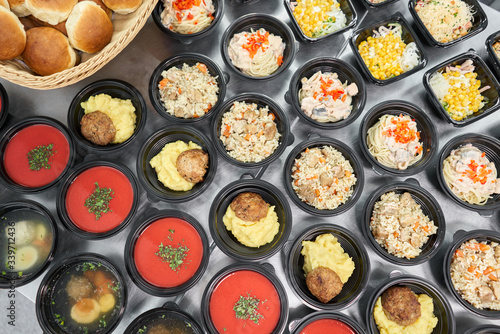 Row of plastic disposable lunch box with healthy natural food. Soups, cream soup, main course with side dish, salads. Food delivery. Lunch in the office.