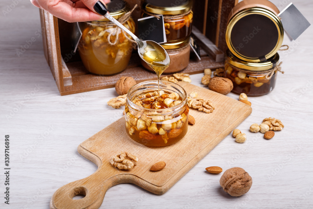 Jar of honey on a wooden board. Honey with nuts. Jar of honey on a wooden board. Honey with nuts.