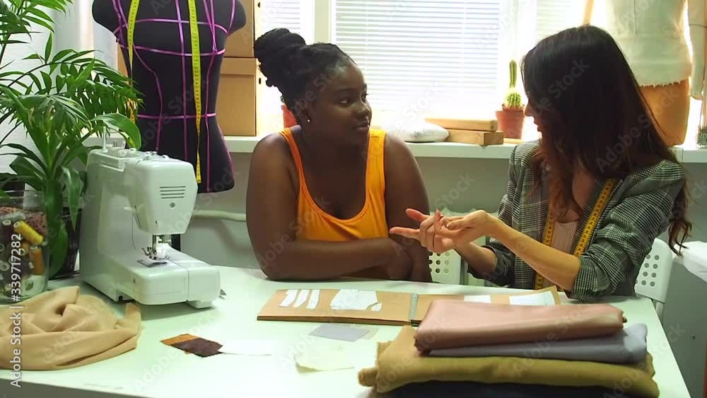 african american woman talking with tailor aboun new clothing collection .sewing courses student with master african american woman talking with tailor aboun new clothing collection .sewing courses student with master