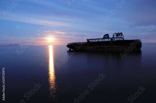 Barco hundido con amanecer de fondo 