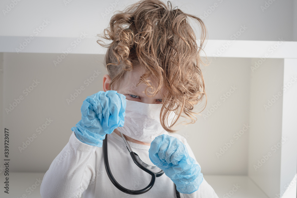 little girl wearing surgical mask and gloves is posing in a fighting ...