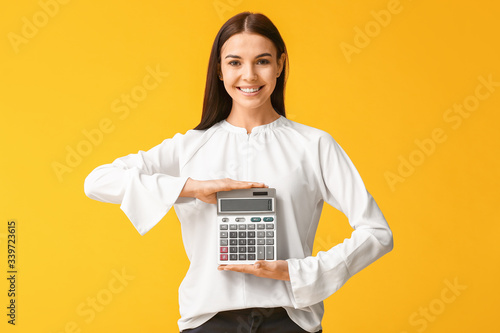 Young woman with calculator on color background photo