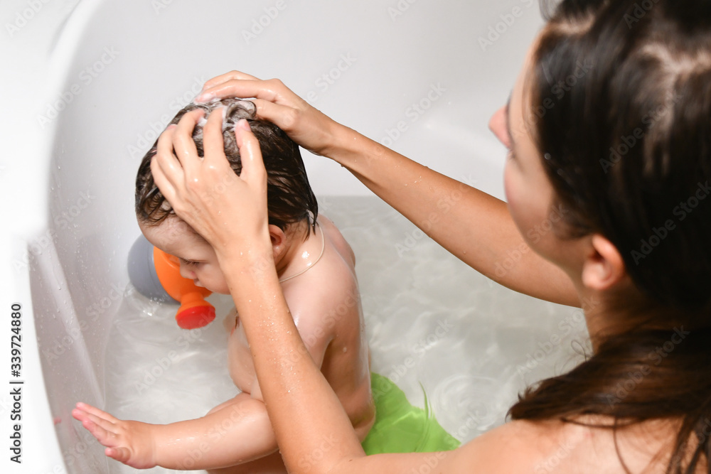 Mom washes the babys head. Joint bathing baby and mom. A symbol of cleanliness and hygiene education. Mom washes the babys head. Joint bathing baby and mom. A symbol of cleanliness and hygiene education.