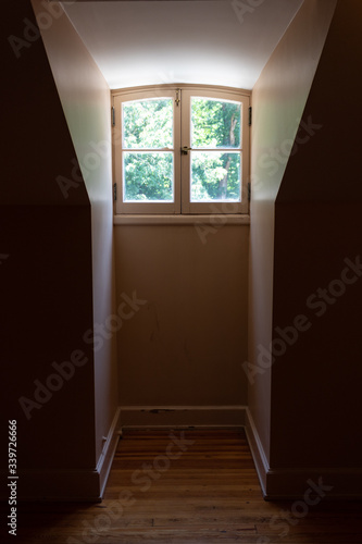 Interior view of a dormer window and very narrow opening in a darkened room  vertical aspect