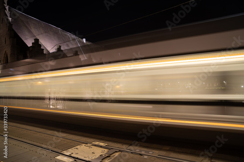 Tram trails on the street of Ghent and monumental column architecture in background, long exposure, blurred motion, city vibe