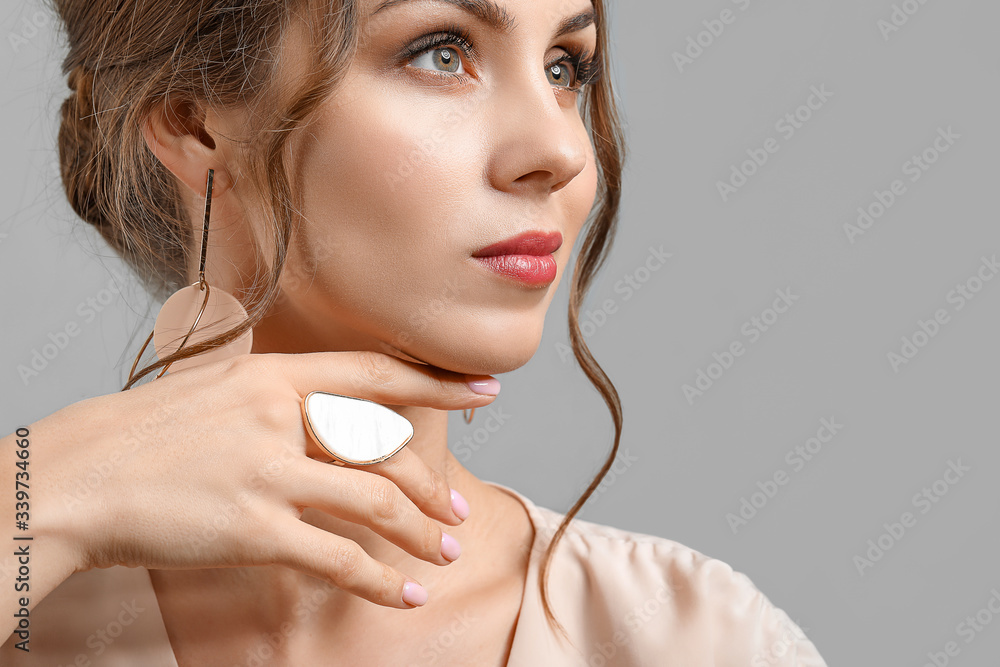 Young woman with beautiful jewellery on grey background Young woman with beautiful jewellery on grey background