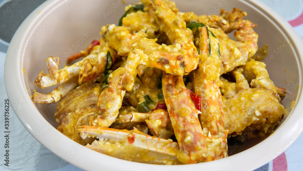 Close up view of buttermilk crab mixed with salted duck eggs in a white bowl. Close up view of buttermilk crab mixed with salted duck eggs in a white bowl.