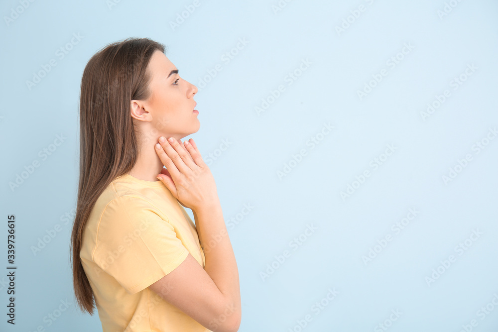 Obraz premium Young woman checking thyroid gland on color background