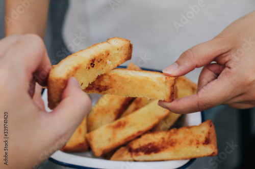 Close up two hand holding homemade garlic bread sticks grilled white butter , sugar and garlic look like toast.Crunchy freshly french bread sticks freshly out of the oven for breakfast.