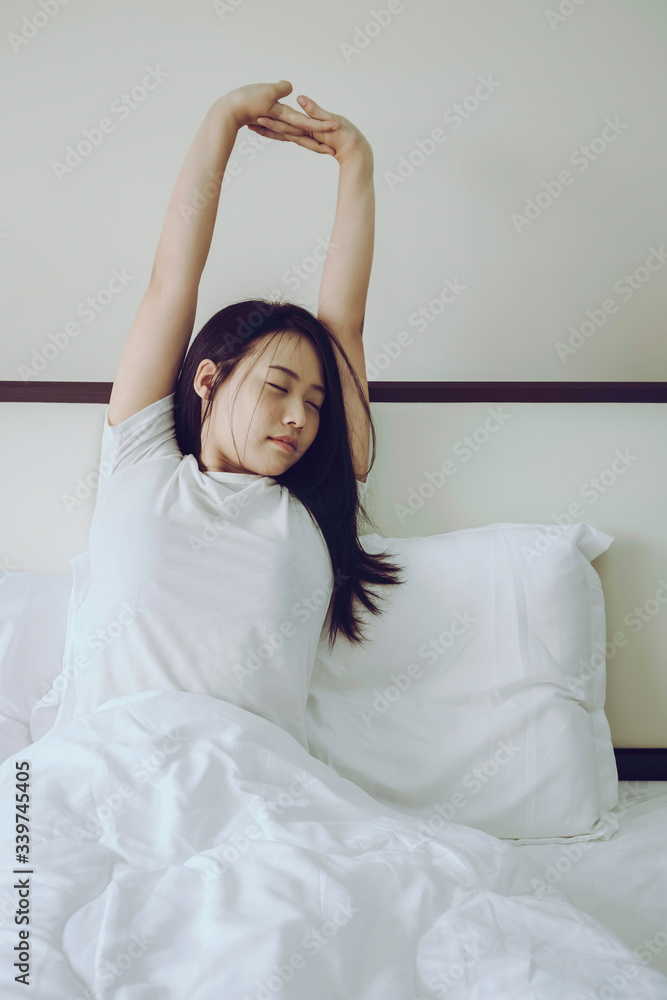 Beautiful Asian woman waking up in the morning from good sleep in weekend taking some rest, Stretches and Gets Up from the Bed, Lifestyle enjoying concept Beautiful Asian woman waking up in the morning from good sleep in weekend taking some rest, Stretches and Gets Up from the Bed, Lifestyle enjoying concept