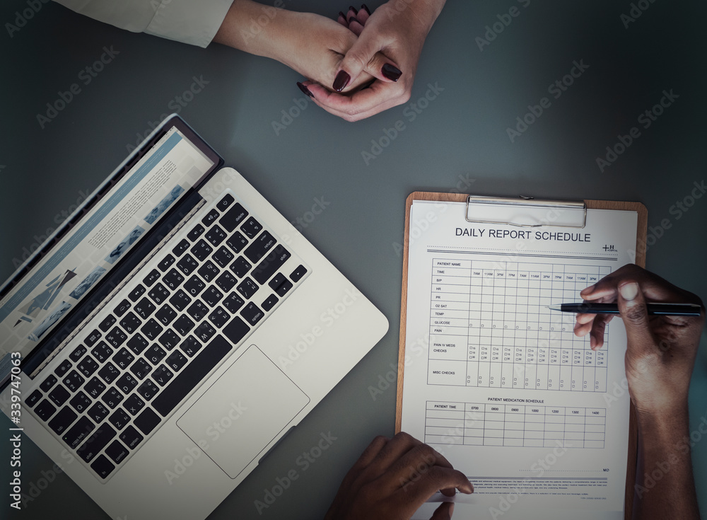 Aerial view of doctor writing patient daily report checklist Aerial view of doctor writing patient daily report checklist