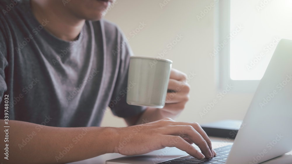 Asian man using laptop at home while sitting the wooden table.Male hands typing on the notebook keyboard. Online training education and freelance work. Computer, laptop and studying remotely. Asian man using laptop at home while sitting the wooden table.Male hands typing on the notebook keyboard. Online training education and freelance work. Computer, laptop and studying remotely.