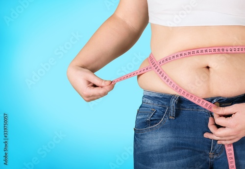 Female fat figure with measuring tape on pastel background