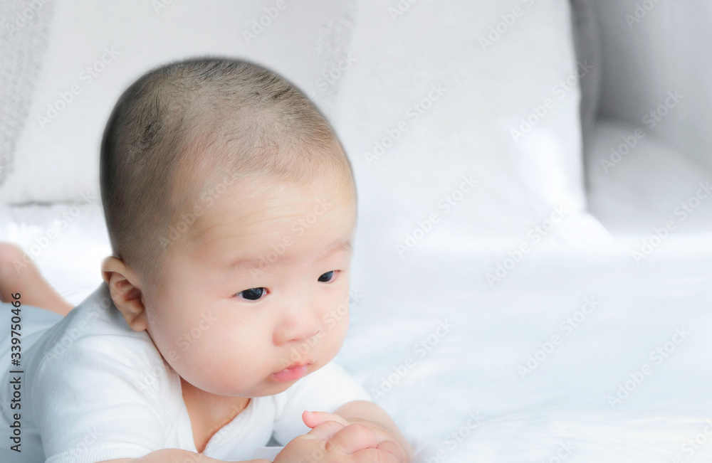 Portrait of a newborn Asian baby boy on the bed , Charming Fat baby 5 month old lies in bed looking with copy space,,soft and selective focus Portrait of a newborn Asian baby boy on the bed , Charming Fat baby 5 month old lies in bed looking with copy space,,soft and selective focus