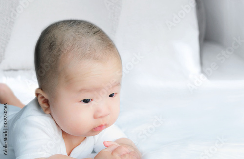 Portrait of a newborn Asian baby boy on the bed , Charming Fat baby 5 month old lies in bed looking with copy space,,soft and selective focus