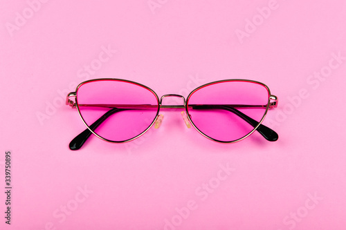 Pink glasses on a pink background. Glamor and style. Glasses for women. The apartment was lying. A place to write. Advertising studio shot of pink glasses.