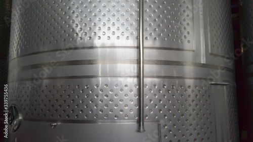 Zoom in and pan up to large dimpled stainless steel wine cylinder, close up