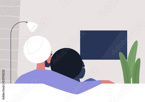 An interracial couple watching TV at home, weekend relaxation, modern lifestyle