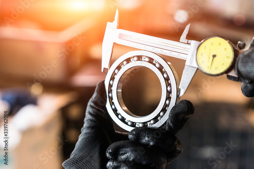 Engineer technician measure a ball bearing with vernier caliper, engineering Engine manufacturing factory Industry. Industrial Concept 
