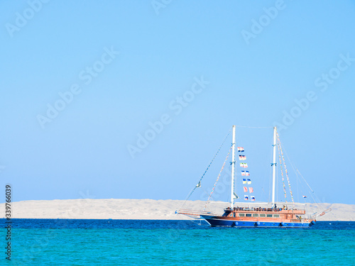 Touristic ship sailing Red Sea  long view. Blue water under clear blue sky. Nature background. Photographed in Egypt in february. Selective soft focus. Blurred background