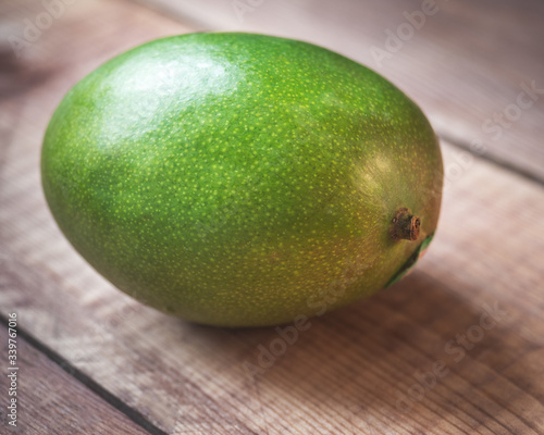 Green mango lies on a wooden table close-up,