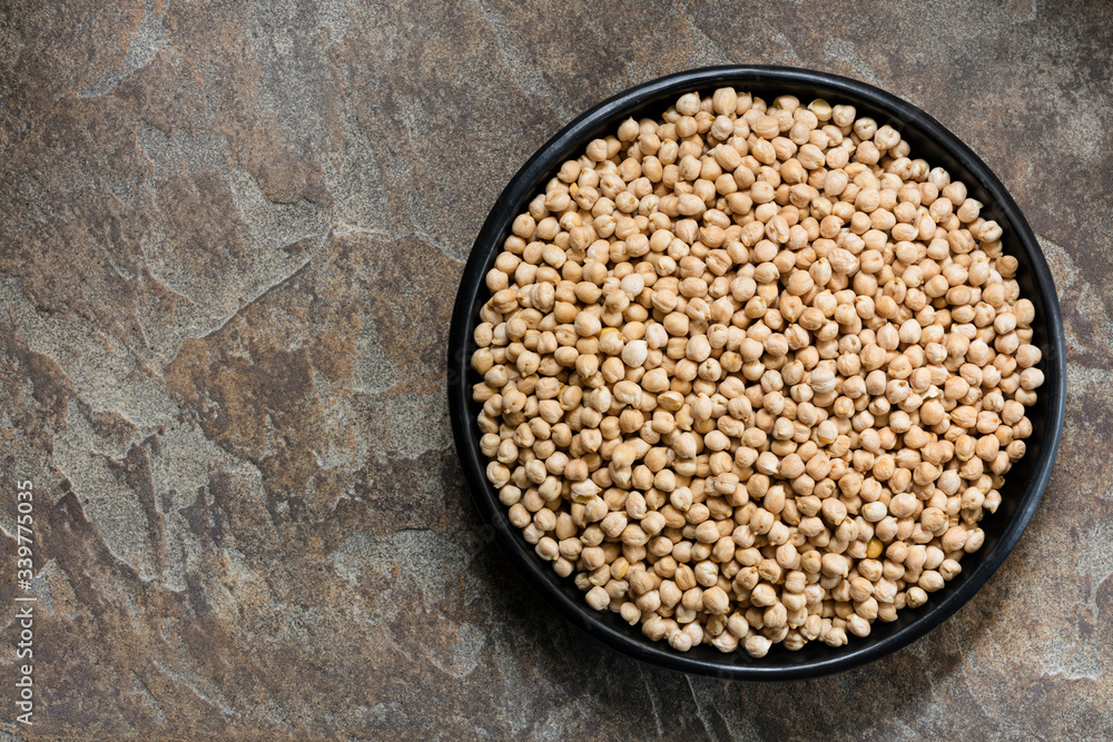 Uncooked Chickpeas in Rustic Black Bowl over Stone Background Top View Uncooked Chickpeas in Rustic Black Bowl over Stone Background Top View