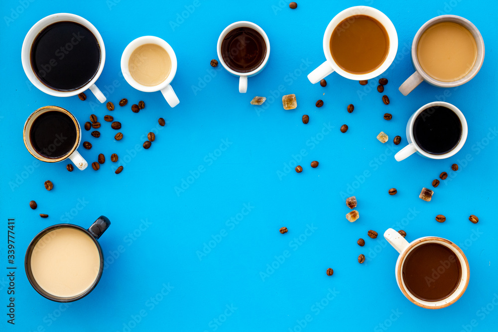Cups of hot drinks on blue table top-down space for text