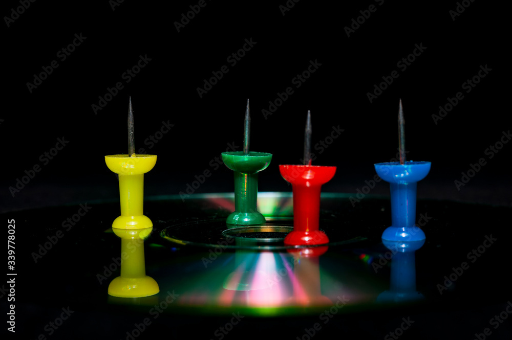 Colorful pushpin on compact disc close up view Colorful pushpin on compact disc close up view
