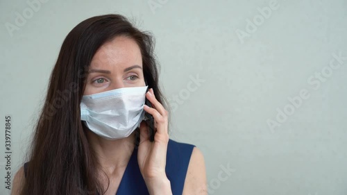 Portrait of brunette business woman in office clothes isolated on gray background close up. Stylish young girl wear protective medical face mask, talking on mobile phone during COVID-19 pandemic. photo