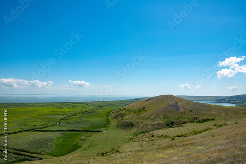 green plain with vegetation and blue sky with clouds