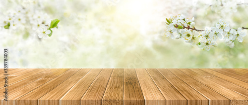 Spring background with white blossoms and sunbeams in front of a wooden table. Spring apple garden on the background photo