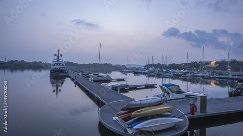 Time-lapse of beautiful sunrise with moving clouds at the marina of luxury yachts, Puteri Harbour, Nusajaya, Johor, Malaysia. photo