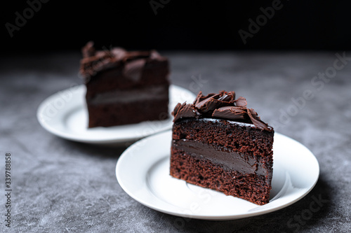 Two slices of sweet Chocolate cakes on the grey table, dark background.