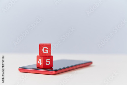 4G, 5G network connecting technology. Mobile generation. Wooden cube with letter G and numbers on modern smartphone photo