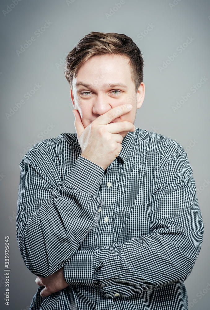 portrait of young man with hand on mouth portrait of young man with hand on mouth