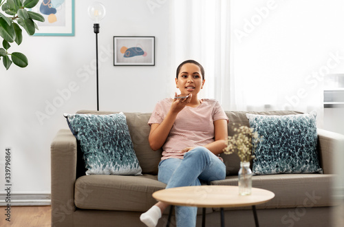 people, technology and communication concept - happy young african american woman using voice command recorder on smartphone at home