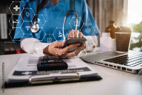 Female doctor working on desk with smartphone and laptop computer and paperwork in the office. Medical and doctor concept.