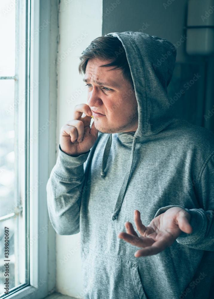 The hooded man talking on the phone at the window The hooded man talking on the phone at the window