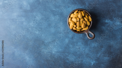 Almonds on a clay pot with nice blue background. Top view. Copy space. Healthy food concept 