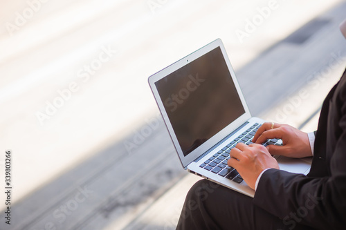 People are sitting at a table and using the laptop outside in the outdoors. Concept of using technology to communicate and can work anywhere, anytime