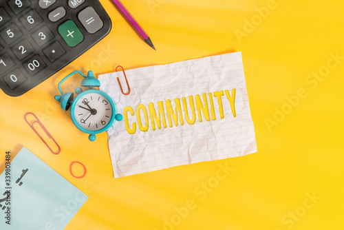 Text sign showing Community. Business photo text group of showing with a common characteristics living together Alarm clock clips note rubber band calculator pencil colored background photo