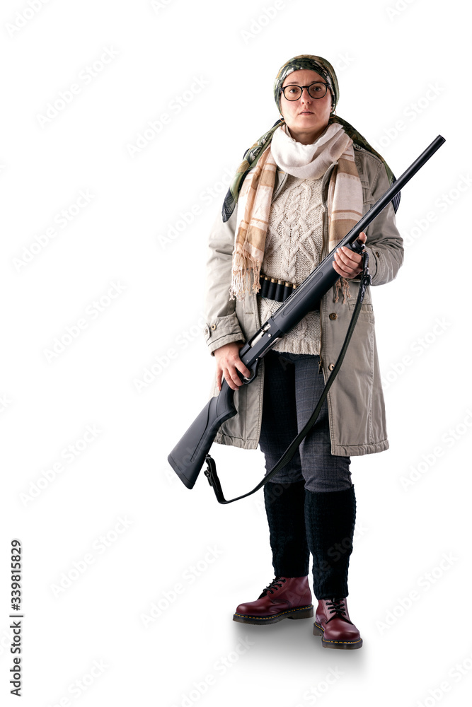 A full-length woman in a light coat, with a scarf on her head, with a gun in her hands and a bandoleer on her belt, poses on a white background. The woman is a hunter. A full-length woman in a light coat, with a scarf on her head, with a gun in her hands and a bandoleer on her belt, poses on a white background. The woman is a hunter.