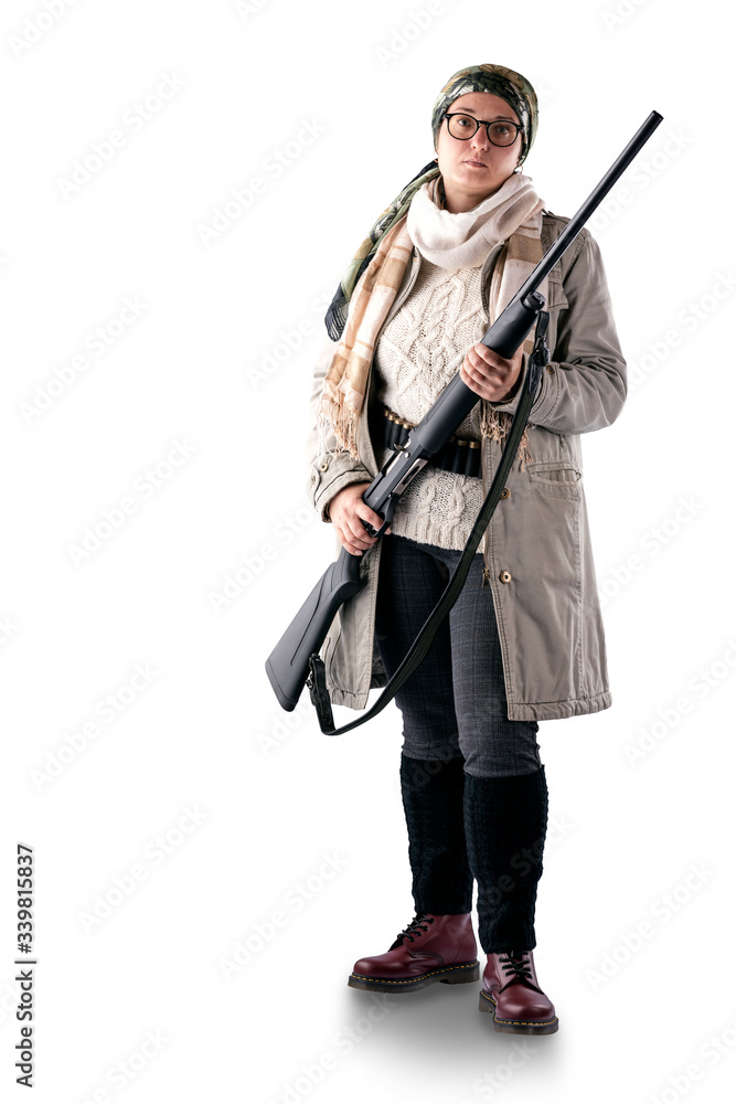 A full-length woman in a light coat, with a scarf on her head, with a gun in her hands and a bandoleer on her belt, poses on a white background. The woman is a hunter. A full-length woman in a light coat, with a scarf on her head, with a gun in her hands and a bandoleer on her belt, poses on a white background. The woman is a hunter.