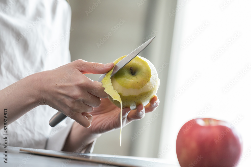 部屋の中でりんごの皮を剥く若い女性の手元 Stock Photo | Adobe Stock