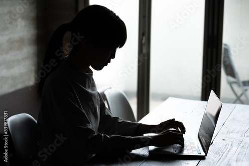 暗い部屋の中でパソコン作業をする若い女性のシルエット姿 Stock Photo Adobe Stock 暗い部屋の中でパソコン作業をする若い女性のシルエット姿 Stock Photo Adobe Stock