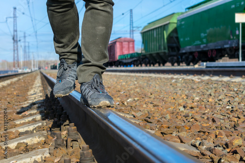 Street tramp in dirty jeans and sneakers walks along the railroad tracks