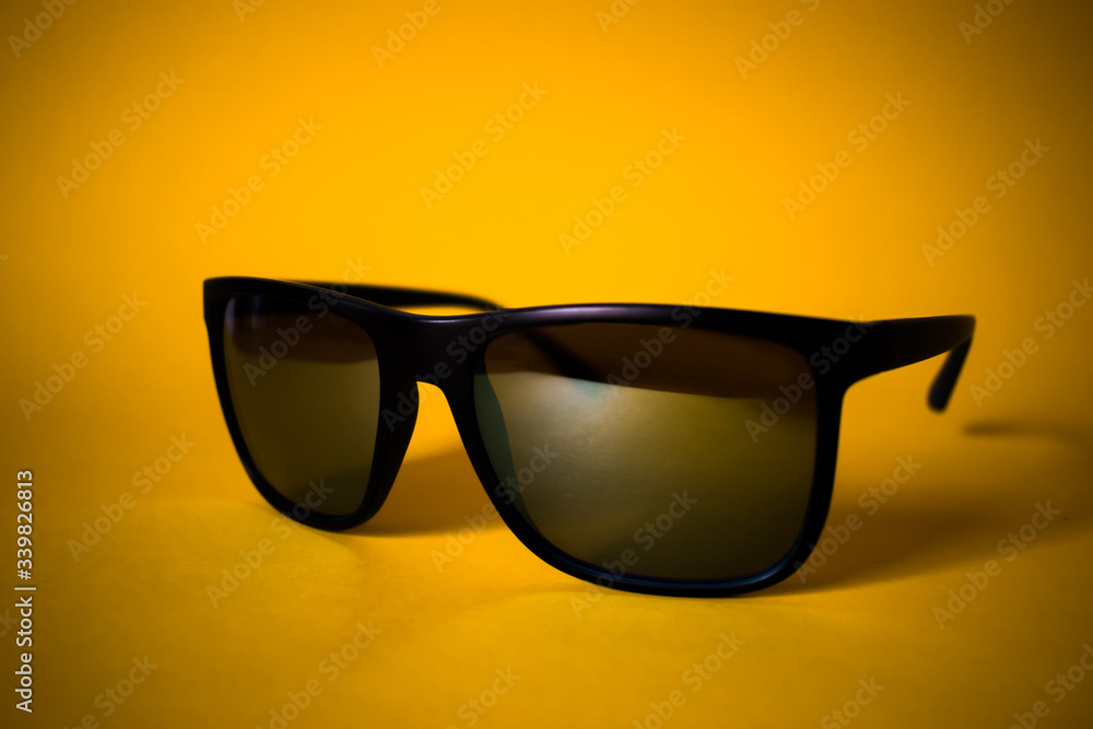 Black sunglasses on yellow background, close up Black sunglasses on yellow background, close up