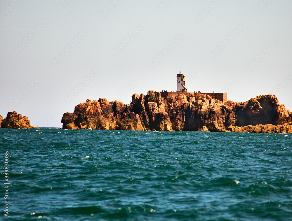 Phare du Paon lighthouse on a rock, view from the sea. Pink granite beach. France. Brittany